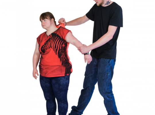 Two individuals standing, one grabbing the other's shirt.