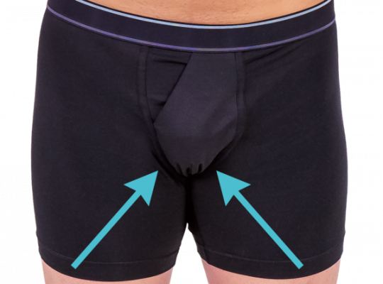 Close-up view of a person wearing black boxer briefs with two blue arrows pointing to the front pouch.