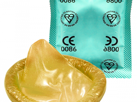 A latex condom next to its teal-colored packaging marked with safety certifications.