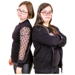 Two women standing back-to-back, both wearing black clothing and glasses.