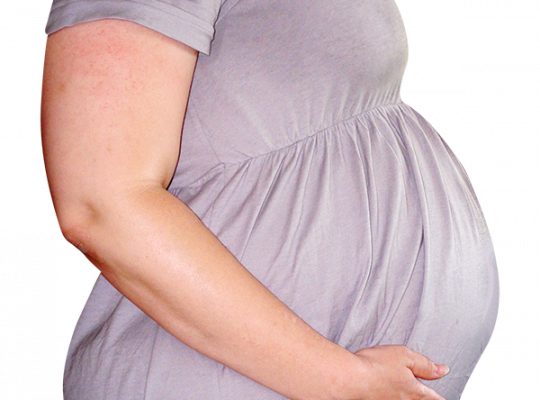 Side profile of a pregnant person in a grey dress cradling their belly.