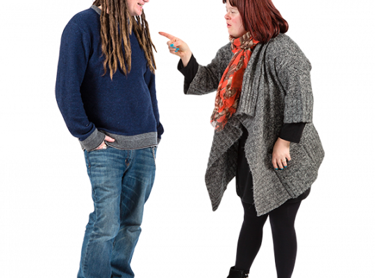 Two individuals having a friendly conversation, one with long dreadlocks and the other with short red hair, set against a white background.