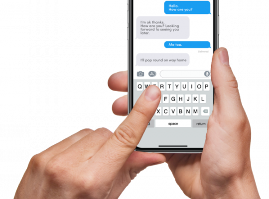 Hands holding a smartphone with a text message conversation on the screen.