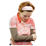 Person with short hair, wearing a pink headband and a patterned shirt, with arms crossed and looking down.