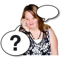 A woman with Down syndrome is talking on a mobile phone. She is wearing a black and white floral dress and a beaded necklace. Two speech bubbles are added to the image, one empty and the other containing a question mark, suggesting a conversation or uncertainty.